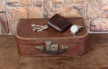 Eski bavul ve kişisel eşyalar ahşap bir masada.