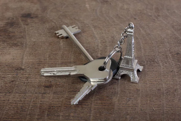 带钥匙链的公寓钥匙 其形式为木制桌子上的埃菲尔铁塔 — 图库照片