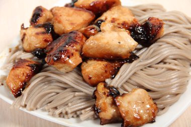 Koyu un makarnası ve seramik tabakta kızarmış et parçaları.