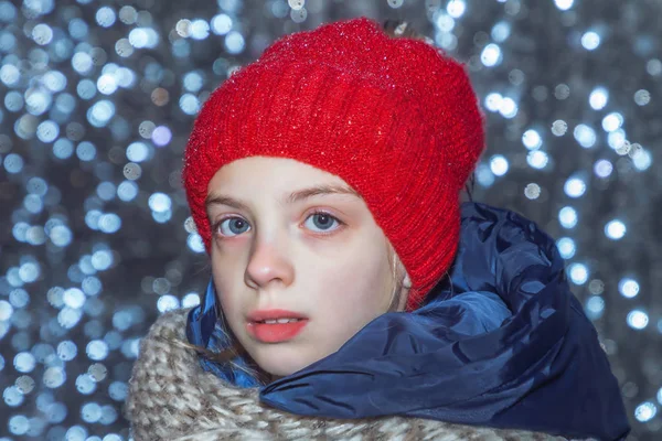 Outdoor close up portrait of young beautiful happy girl wearing white knitted beanie hat.