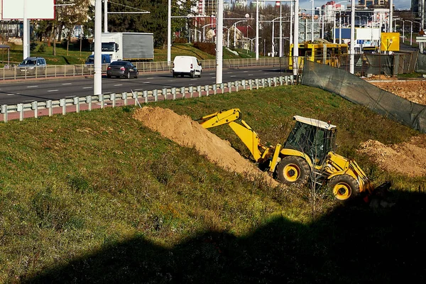 Gelber Baggerlader gräbt unter der Straße — Stockfoto