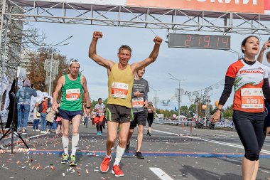 15 Eylül 2019 Minsk Belarus başarılı sporcuları bitiş çizgisini geçerken ellerini kaldırıyorlar. Elleri havada fitness adamı, maratondan sonra spor amaçlarını kutluyor.