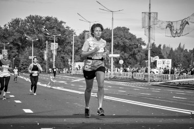 15 Eylül 2019 'da Minsk Belarus' ta siyah beyaz bir maraton yarışında bir kadın şehir yolunda koşuyor.