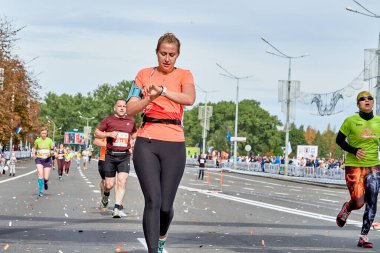 15 Eylül 2019 Minsk Belarus. Bir kadın maraton koşuyor ve akıllı saatindeki kalp atış hızını kontrol ediyor.