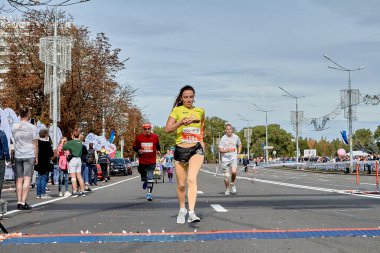 15 Eylül 2019 Minsk Belarus. Bir atlet maratonun bitiş çizgisine koşuyor ve akıllı telefonundaki kalp atış hızını kontrol ediyor.