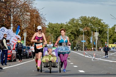 15 Eylül 2019 Minsk Belarus Maratonu 'nda iki kadın ve tekerlekli sandalyedeki engelli bir kız şehir yolunda maraton koşuyor.