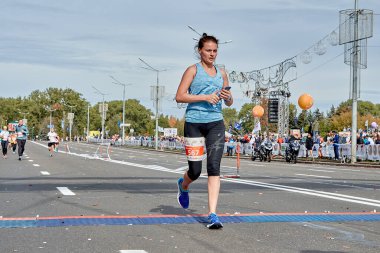 15 Eylül 2019 Minsk Belarus elinde akıllı telefonuyla aktif bir kadın şehir maratonunun bitiş çizgisini geçiyor.