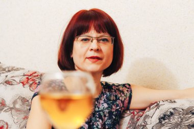 Bir kadın bir bardak şarabın önünde oturuyor.