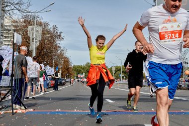 15 Eylül 2019 Minsk Belarus. Katılımcıların bitiş çizgisini geçtiği bir maraton. Bir kadın ellerini kaldırarak karşıya geçiyor.