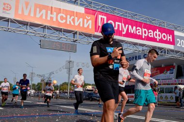 15 Eylül 2019 Minsk Belarus Sporcusu maratonun bitiş çizgisini geçerken telefona bakar.