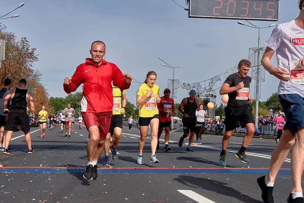 2018年9月15日ミンスクベラルーシハーフマラソンミンスク201感情的なランナーが市内のアスファルトの道路上でマラソンを実行します フィニッシュラインを横断する赤いトラックスーツのマラソン男子選手 — ストック写真