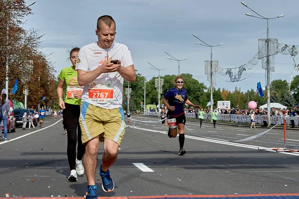 2019年9月15日 这位运动员跑到马拉松终点 用智能手机检查心率监测器 跑马拉松的快女人 — 图库照片