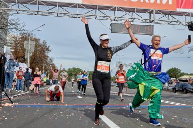 15 Eylül 2019 Minsk Belarus başarılı sporcuları bitiş çizgisini geçerken ellerini kaldırıyorlar. Fitness adamı dizlerinin üzerinde bitiş çizgisini geçiyor.