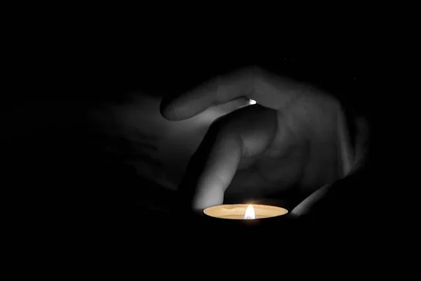 Bir Adamın Eli Masanın Üzerine Yanan Bir Mum Koyar Karanlıkta — Stok fotoğraf