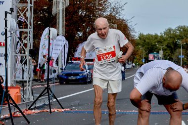 15 Eylül 2019 Minsk Belarus Yaşlı bir katılımcı yorgun bir atletin yanındaki maratonun bitiş çizgisini geçiyor