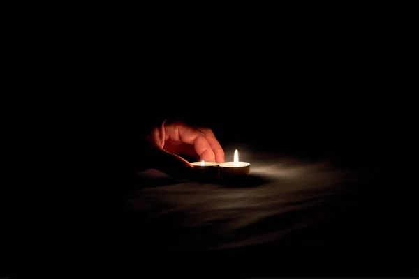 追悼日那天 一只人类的手把一根炽热的蜡烛放在一张无色的桌子上 — 图库照片