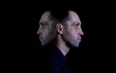 İki taraflı bir insan portresi, karanlık bir arkaplanda psikolojik fotoğraf.