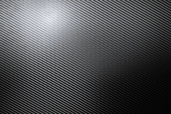 Detalle estructural de una lámina de fibra de carbono industrial en una vista de marco completo que muestra el patrón diagonal repetido mientras la luz juega a través de la superficie en una textura de fondo — Foto de Stock