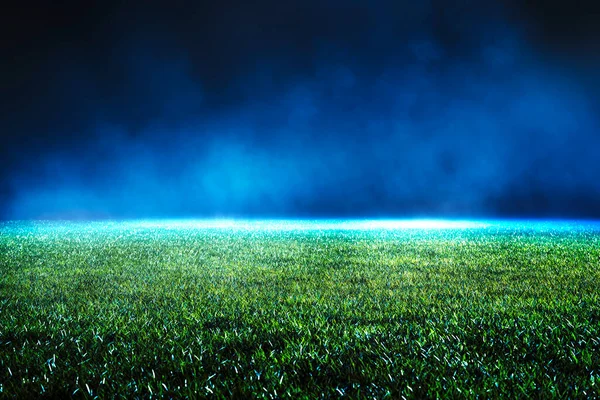 Night low view of maintained lawn at football stadium. Beams of light showing light effects at fog.