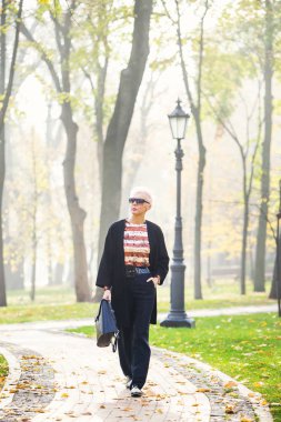 Sonbahar parkında şık sarışın bir kadın.