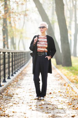 Sonbahar parkında şık sarışın bir kadın.