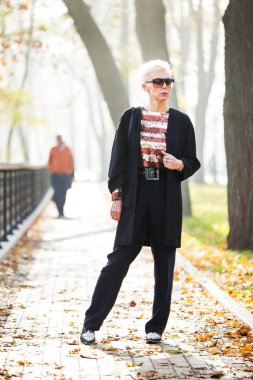 Sonbahar parkında şık sarışın bir kadın.