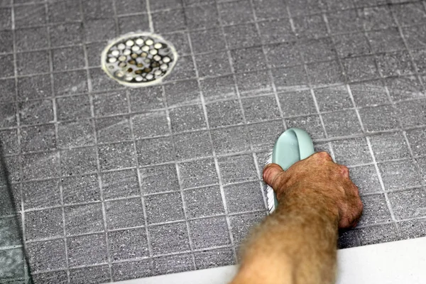 Mão masculina esfregando chuveiro piso — Fotografia de Stock