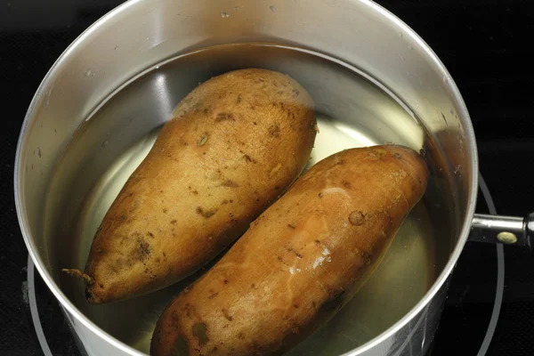 Twee sinaasappel zoete aardappelen in water — Stockfoto