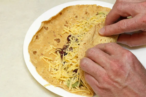 Två händer rullande en vegetarisk Burrito — Stockfoto
