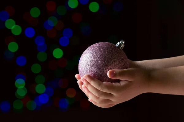 Fialová vánoční ples v dětském rukou na černém pozadí — Stock fotografie