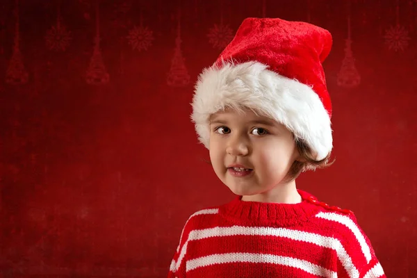Schattig klein meisje in de rode kerstmuts op de rode achtergrond — Stockfoto
