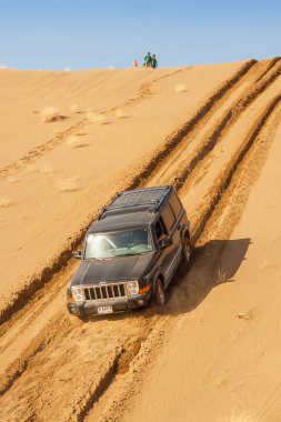 MÜZİKA, OMAN - 5 Mart 2006: Dubai kayıtlı bir Jeep Komutanı 4x4 SUV Umman Sultanlığı 'nın iç kısımlarında arazi aracını sürerken bir kum tepesi pazarlığı yapar.