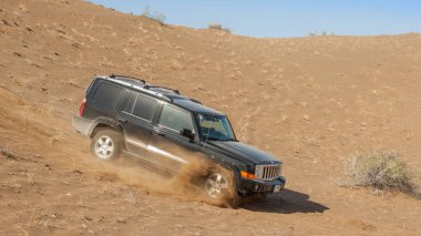 MÜZİKA, OMAN - 5 Mart 2006: Dubai kayıtlı bir Jeep Komutanı 4x4 SUV Umman Sultanlığı 'nın iç kısımlarında arazi aracını sürerken bir kum tepesi pazarlığı yapar.