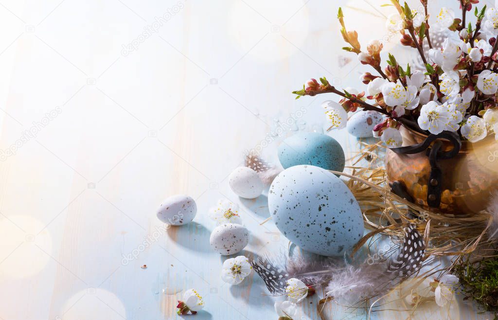 Happy Easter;  Easter eggs and sprig flowers on blue table backg