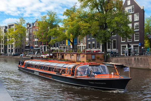 Ausflugsboot mit Touristen während einer Besichtigungstour durch die Kanäle von Amsterdam — Stockfoto