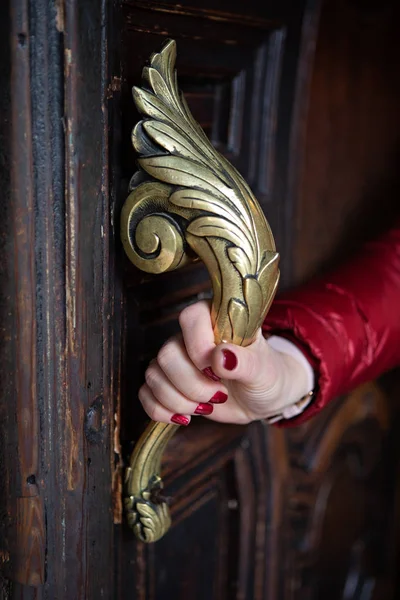 Mão feminina segura o punho da porta de latão ornamentado — Fotografia de Stock