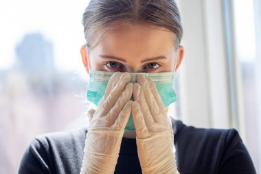 Genç bayan cerrahi maske ve koruyucu eldiven takıyor. Covid-19 salgın konsepti