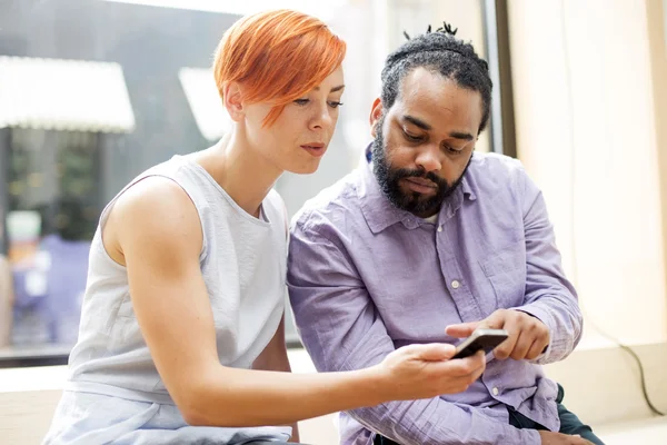 Multiracial couple using smartphone — Stock Photo, Image