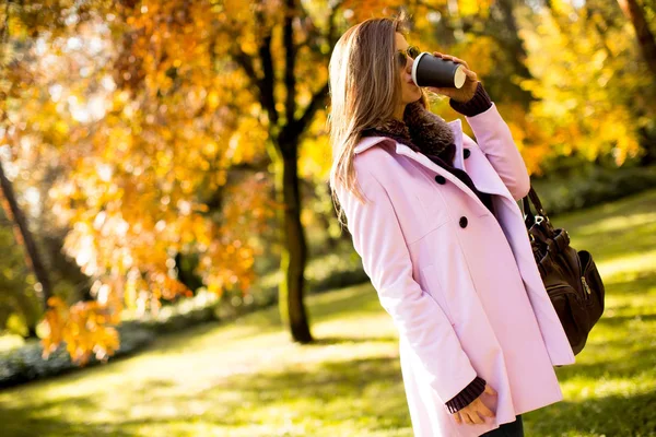 Mujer joven con café en el parque de otoño — Foto de Stock