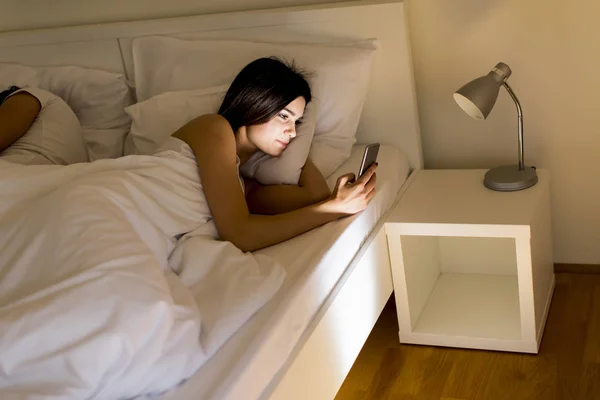 Vrouw met telefoon in bed — Stockfoto