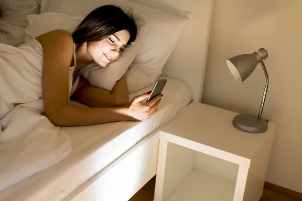 Woman with phone in bed — Stock Photo, Image