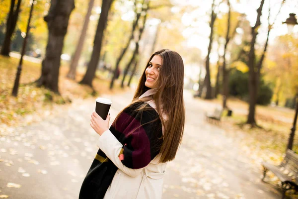 秋の公園でコーヒーを飲みながら若い女性 — ストック写真