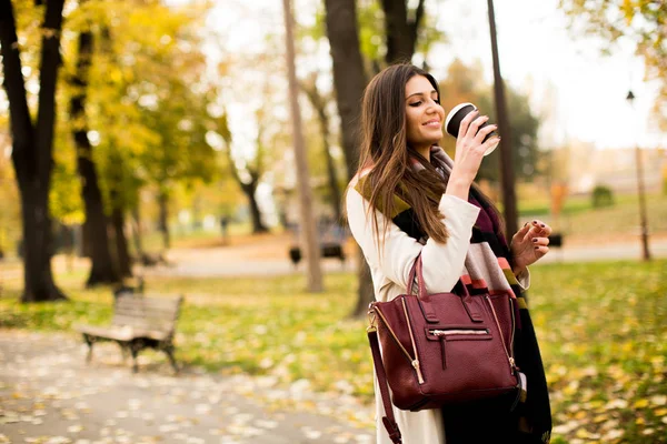 秋の公園でコーヒーを飲みながら若い女性 — ストック写真