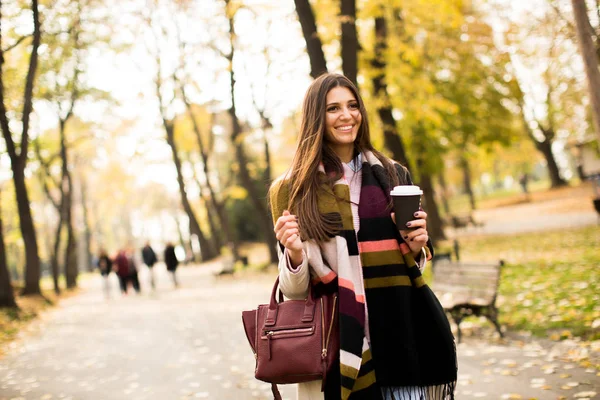 咖啡在秋天的公园里的年轻女子 — 图库照片