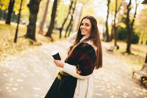 Ung kvinde med kaffe i efteråret park - Stock-foto