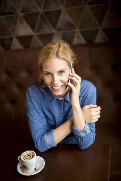 Mulher bonita com telefone no café — Fotografia de Stock