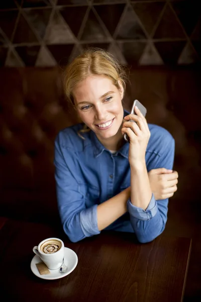 Mulher bonita com telefone no café — Fotografia de Stock