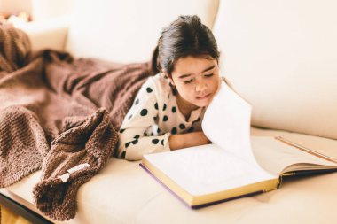 Küçük kız kitap okuyor.