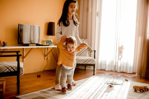 Mädchen hilft kleiner Schwester beim Gehen — Stockfoto