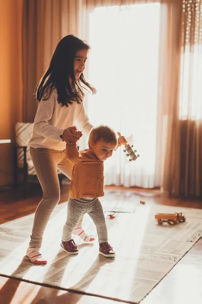 Menina ajudando a irmã bebê a andar — Fotografia de Stock